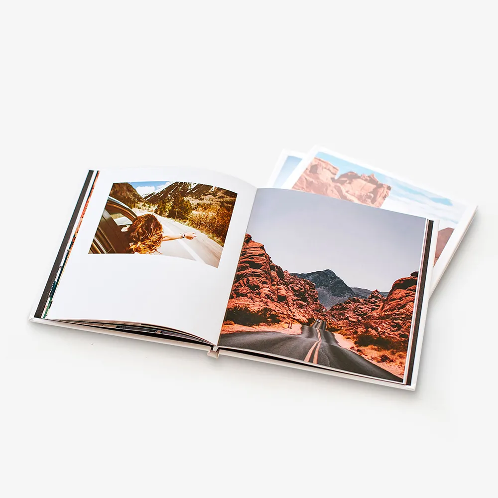An open hardcover photo book showing travel photos across two pages