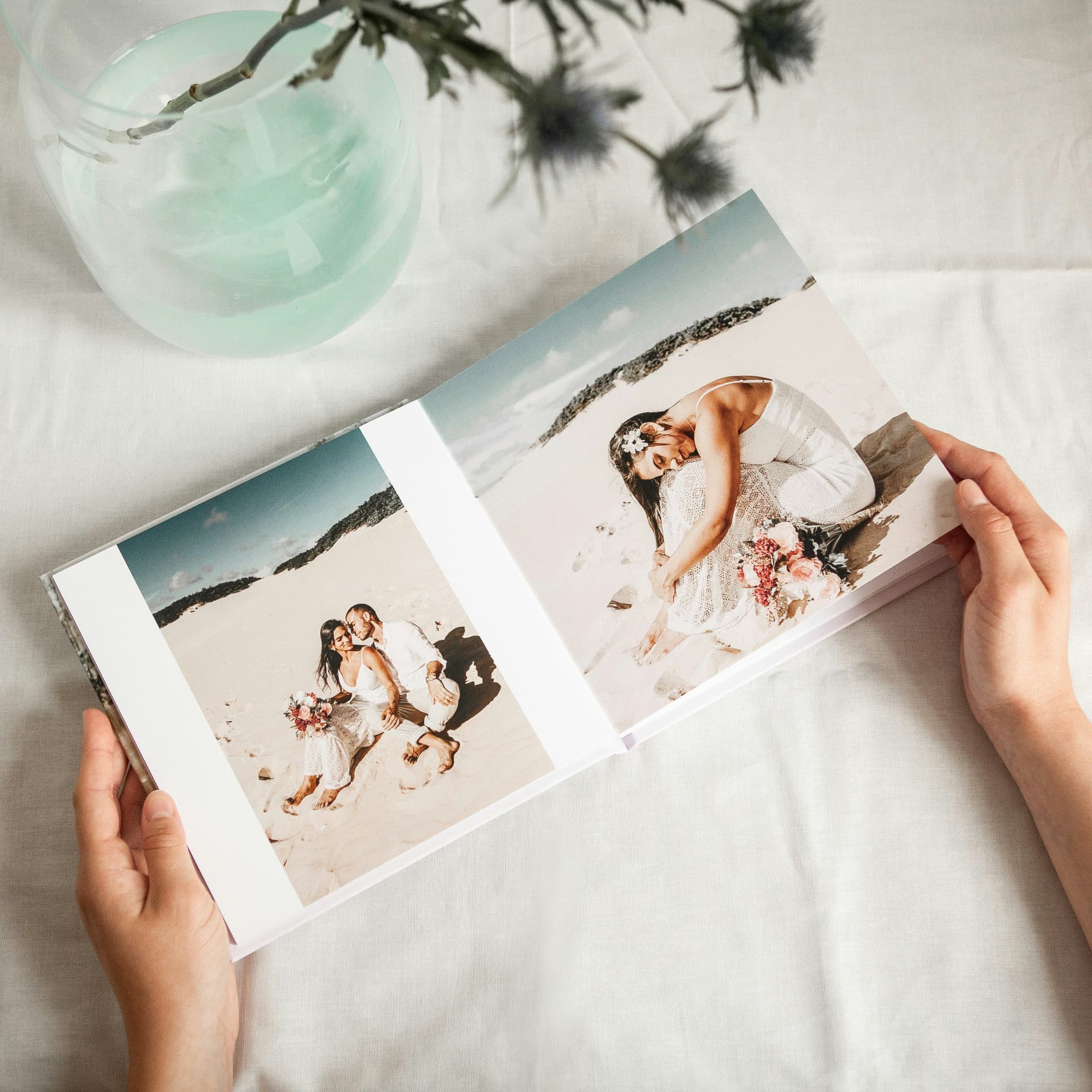 Hands holding an open square hardcover photo book of wedding photos